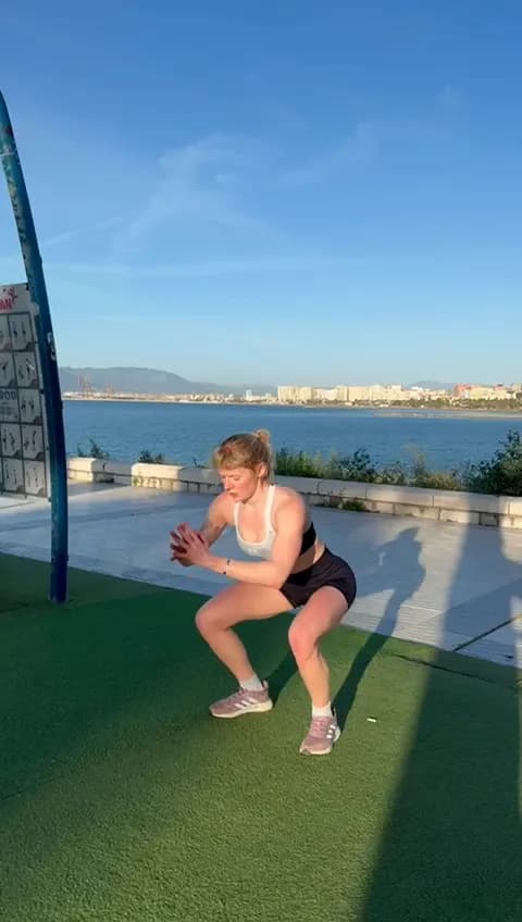 Kitty mid-squat on an outdoor training area by the sea